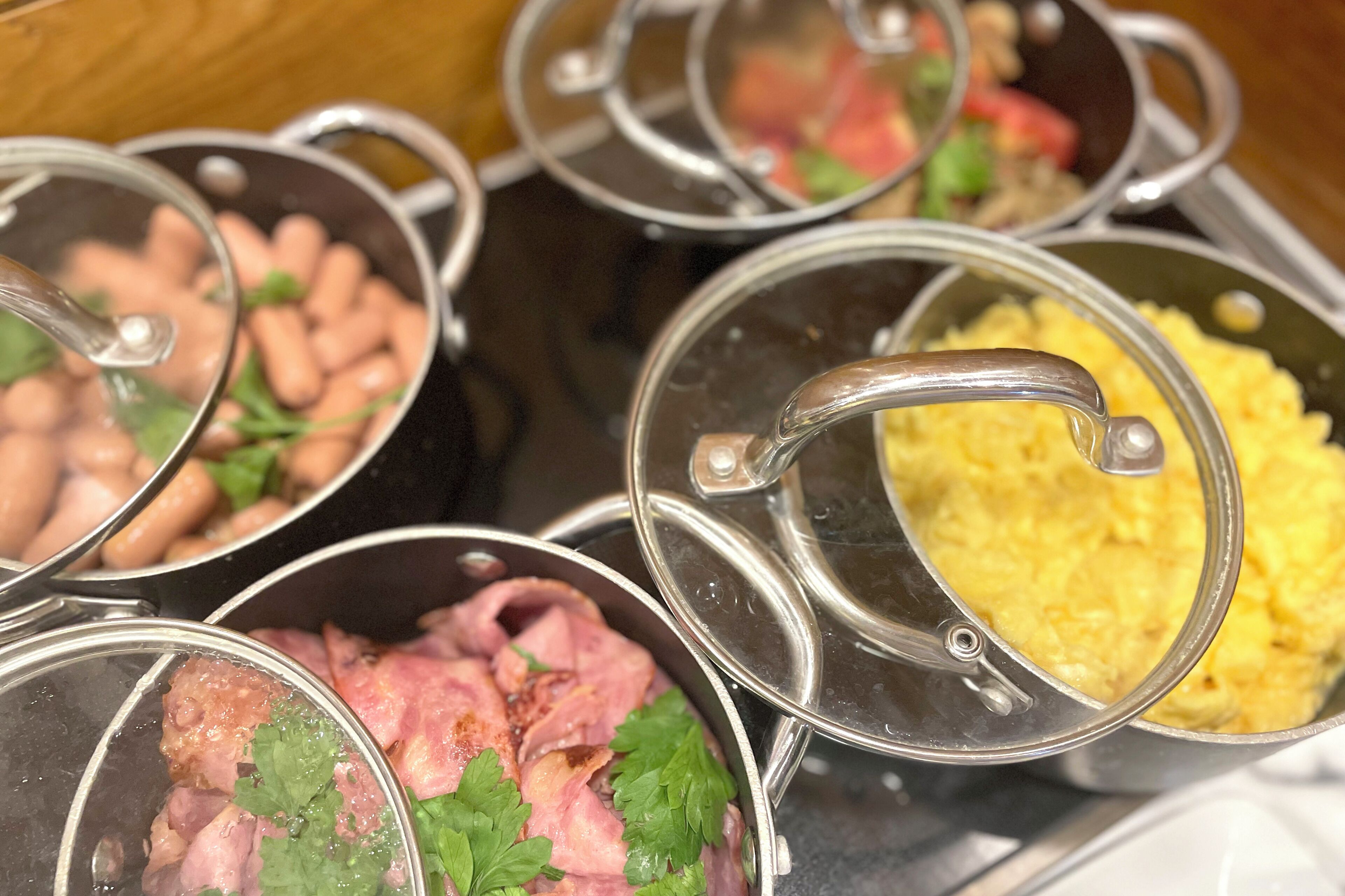 Multiple pots with lids, containing various food items like beans, meat, and scrambled eggs.