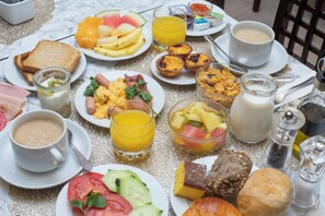 A breakfast table with various food items, drinks, and condiments.