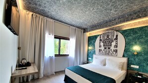 A hotel room with a bed, a desk, a chair, a window with curtains, a wall with a patterned design, and a ceiling with a textured design. - Casual Inca Porto Hotel by Casual Hoteles (Porto)
