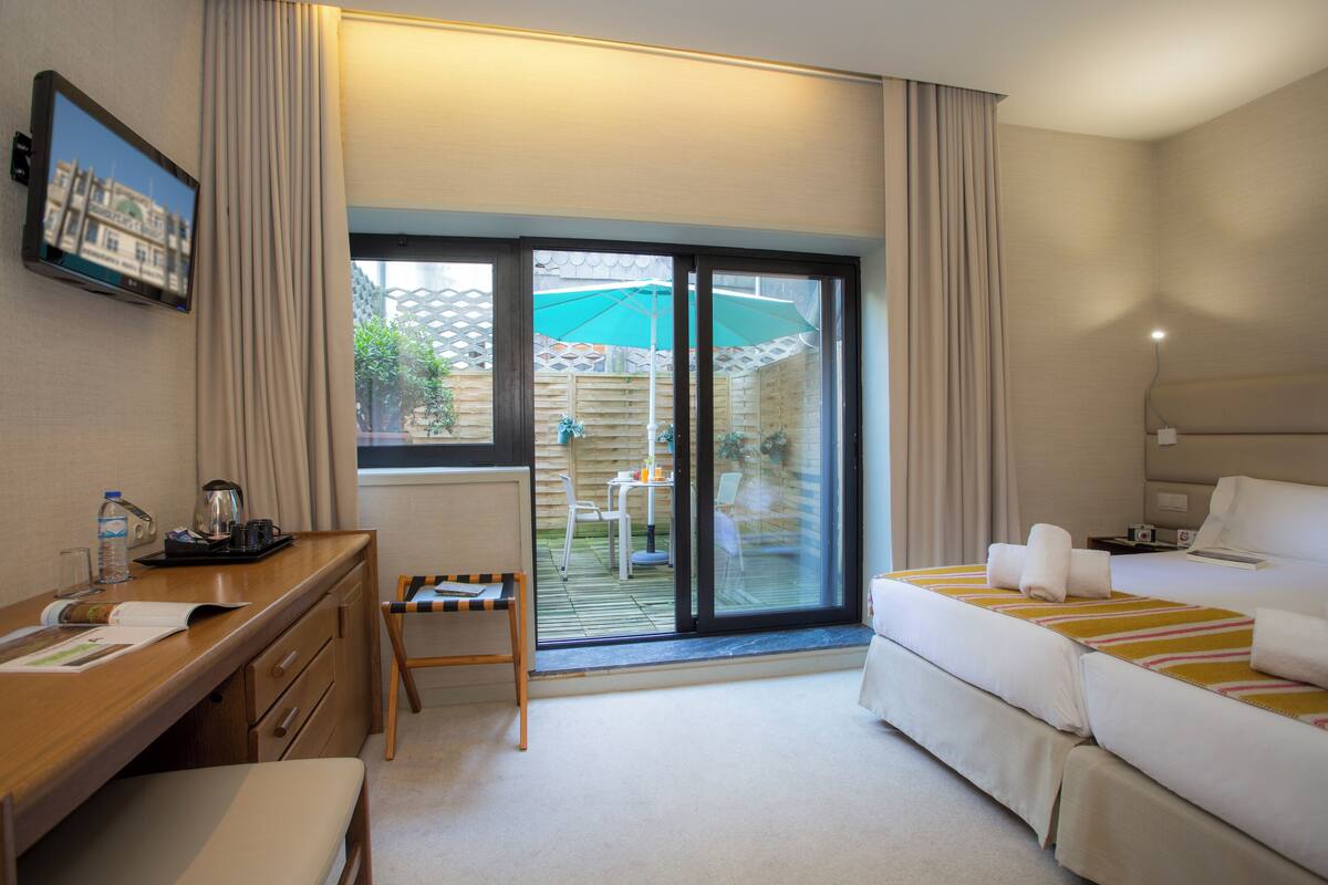 A hotel room with a desk, chair, bed, and a view of the outdoor area.