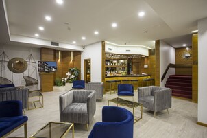 A modern lounge area with seating, a bar, and a staircase.