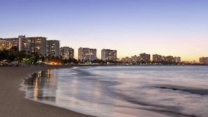 A beachfront hotel with multiple high-rise buildings in the background, a sandy beach, and calm ocean waters. - Embassy Suites by Hilton San Juan Hotel & Casino (Carolina)
