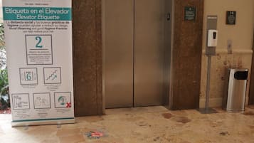 An elevator with a sign about elevator etiquette and social distancing.