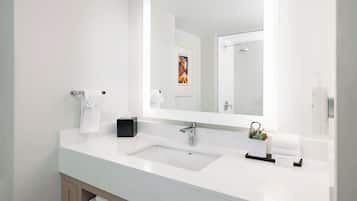 A modern bathroom with a white sink, a large mirror, and a towel rack.