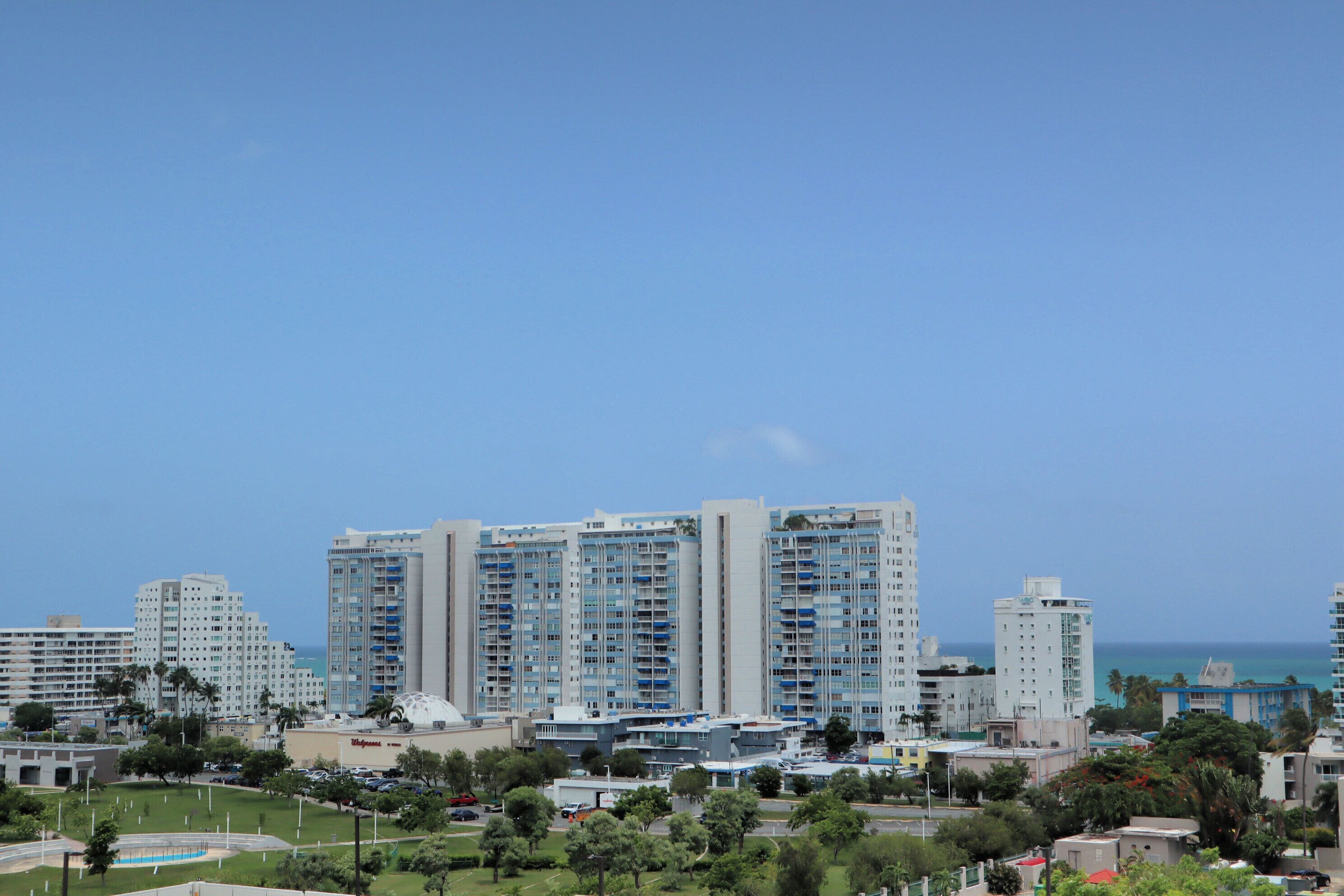 A high-rise hotel with multiple floors, a parking area, and a view of the ocean.