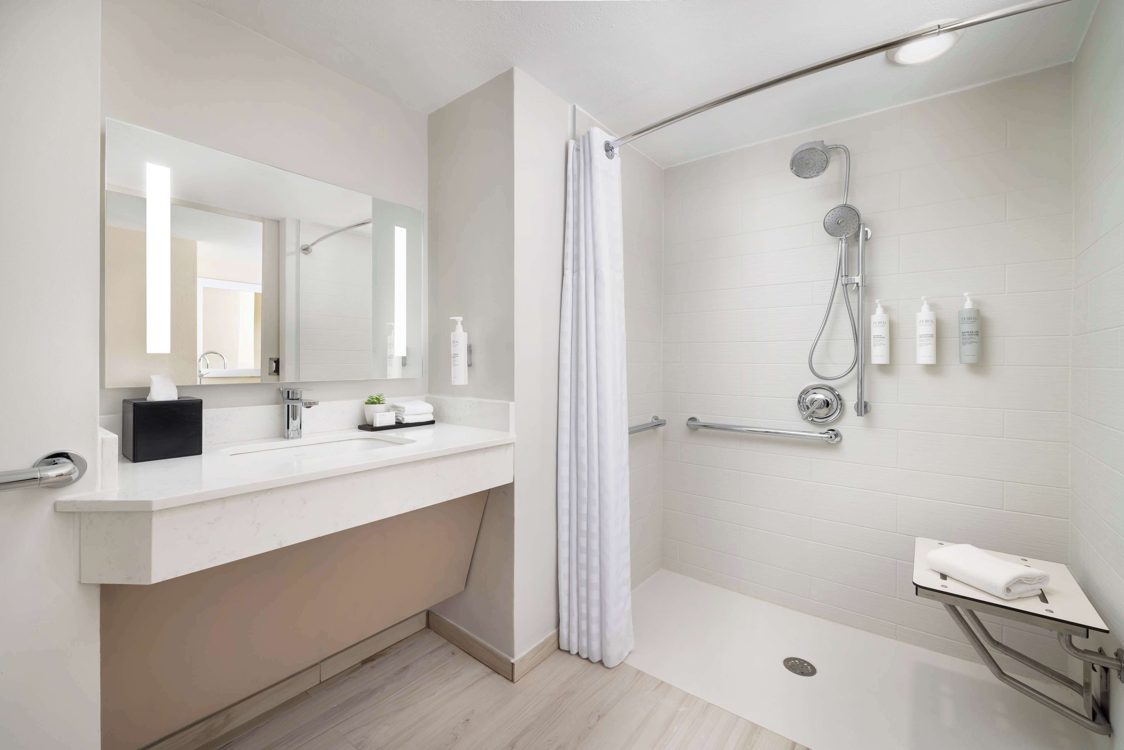 A modern bathroom with a shower, a vanity with a mirror, and a towel rack.
