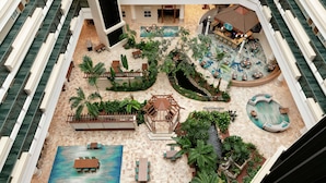 A rooftop pool area with multiple seating areas, a small waterfall feature, and lush greenery. - Embassy Suites by Hilton San Juan Hotel & Casino (Carolina)