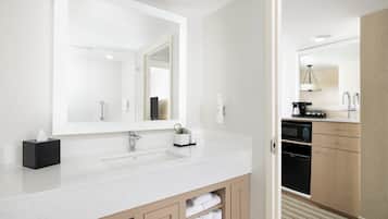 Une salle de bain moderne avec un grand miroir, deux lavabos et une machine à café.
