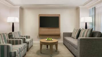 A living room with two sofas, a coffee table, and a flat-screen TV mounted on the wall.