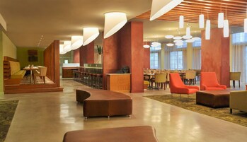 A spacious lobby with a bar area, seating arrangements, and modern lighting fixtures.