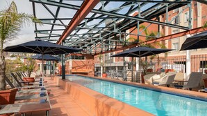 Ein Poolbereich mit Liegestühlen, Sonnenschirmen und einem klaren, blauen Pool.