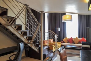 A modern interior with a staircase, a sofa set, and a television.