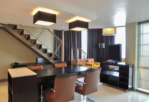 A modern living room with a staircase, a dining area, and a TV.
