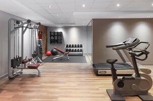 A gym with exercise equipment, a treadmill, and a wall-mounted dumbbell rack.