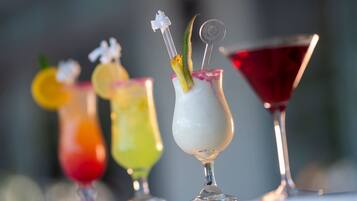 A variety of colorful cocktails in different glassware, including a martini glass and a highball glass.