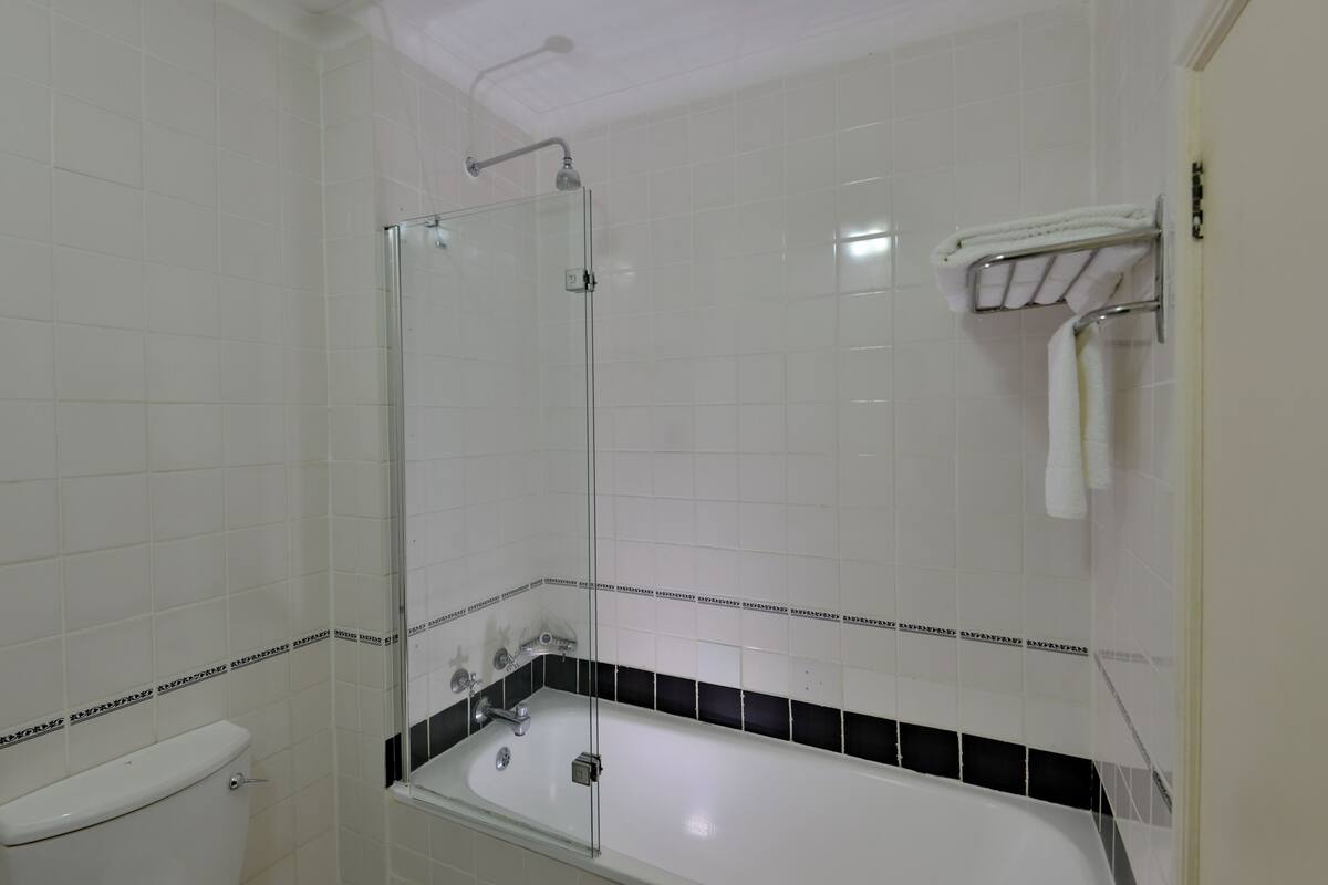A bathroom with a glass-enclosed shower, a white bathtub, and a toilet.