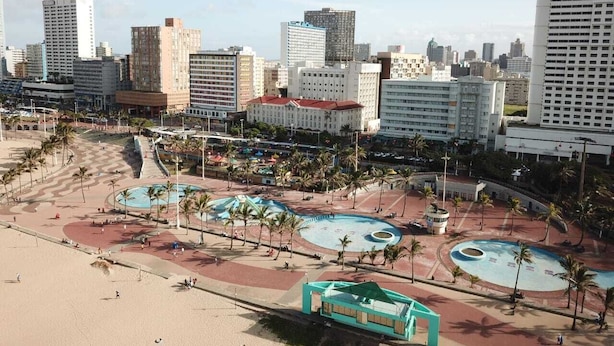 A coastal cityscape with a beach, palm trees, and a large public square with fountains. - The Balmoral Hotel (Durban)