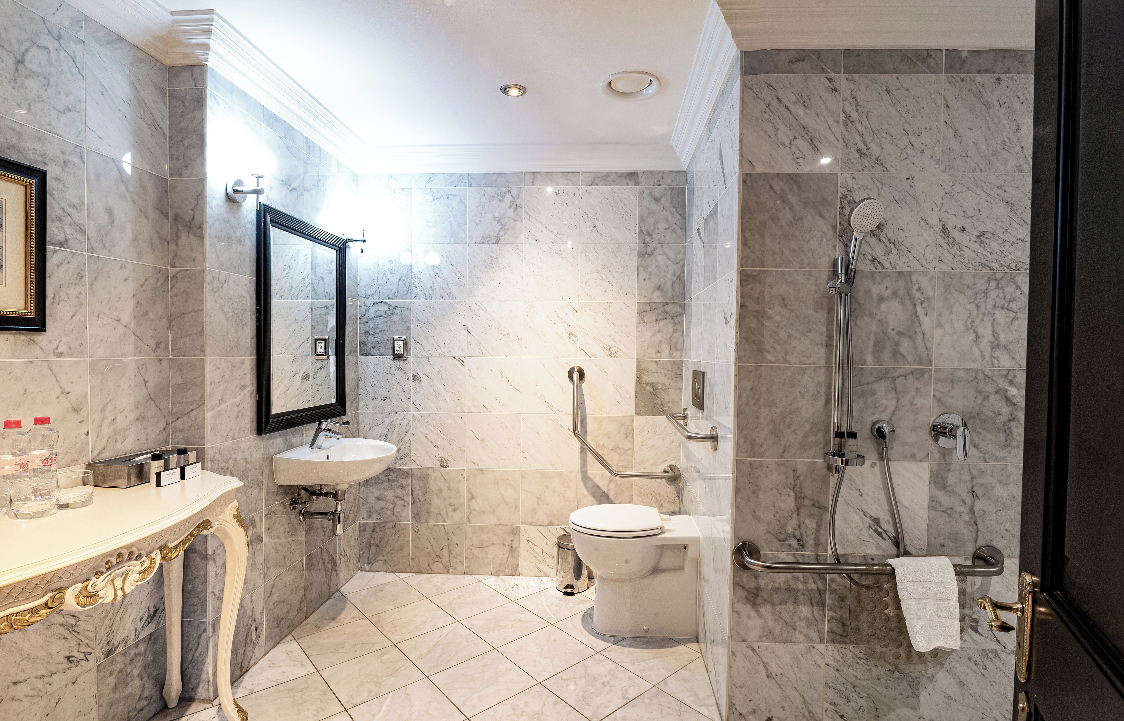 A modern bathroom with a marble floor, a sink, a toilet, and a shower area.