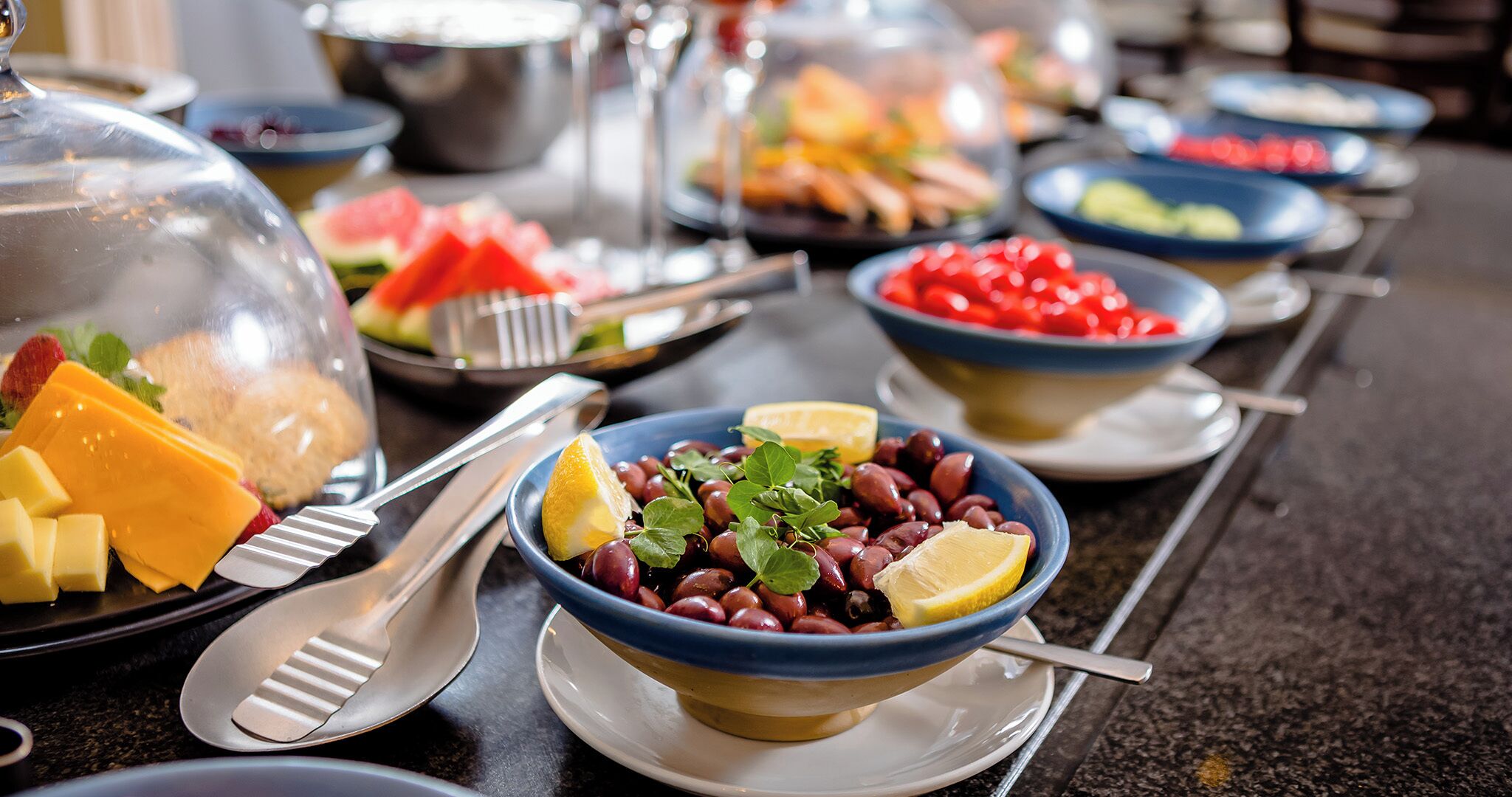A buffet with various dishes including cheese, beans, and fruits.