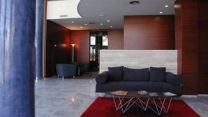 A modern lobby with a dark-colored sofa, a red rug, and a minimalist design.