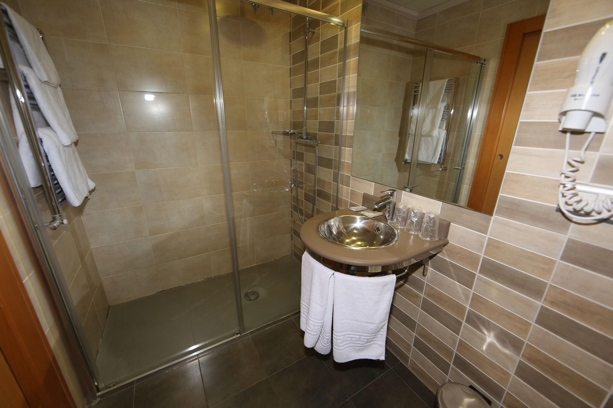 A bathroom with a glass shower enclosure, a sink with a mirror, and a towel rack.