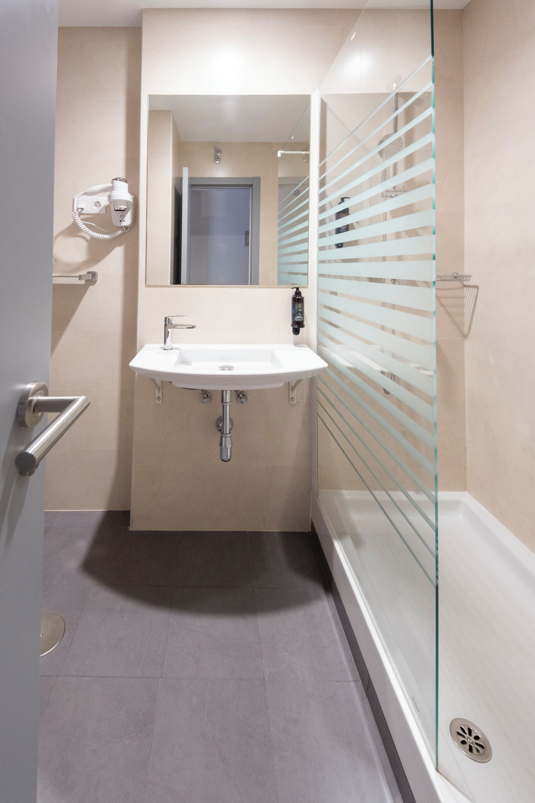Ein modernes Badezimmer mit Duschkabine aus Glas, einem weißen Waschbecken und einem Spiegel darüber.