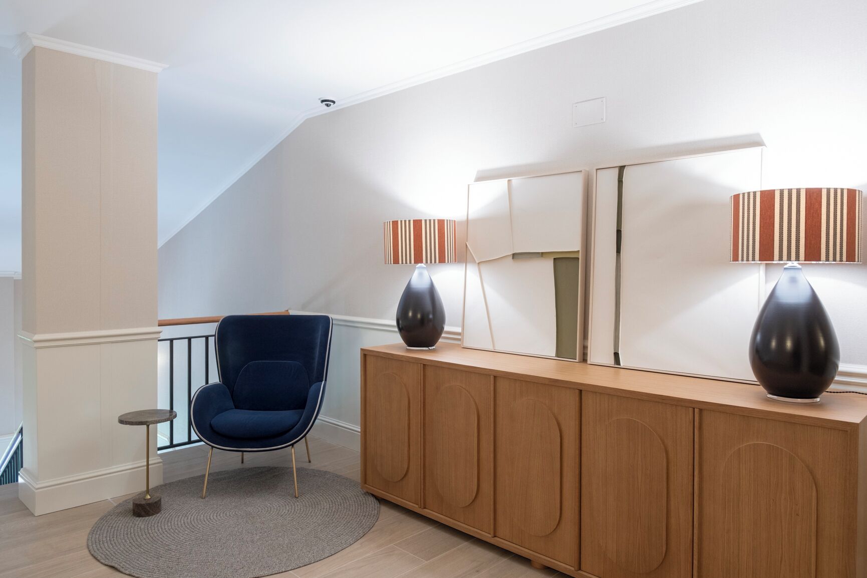 Una habitación con una silla azul, un armario de madera y dos lámparas.