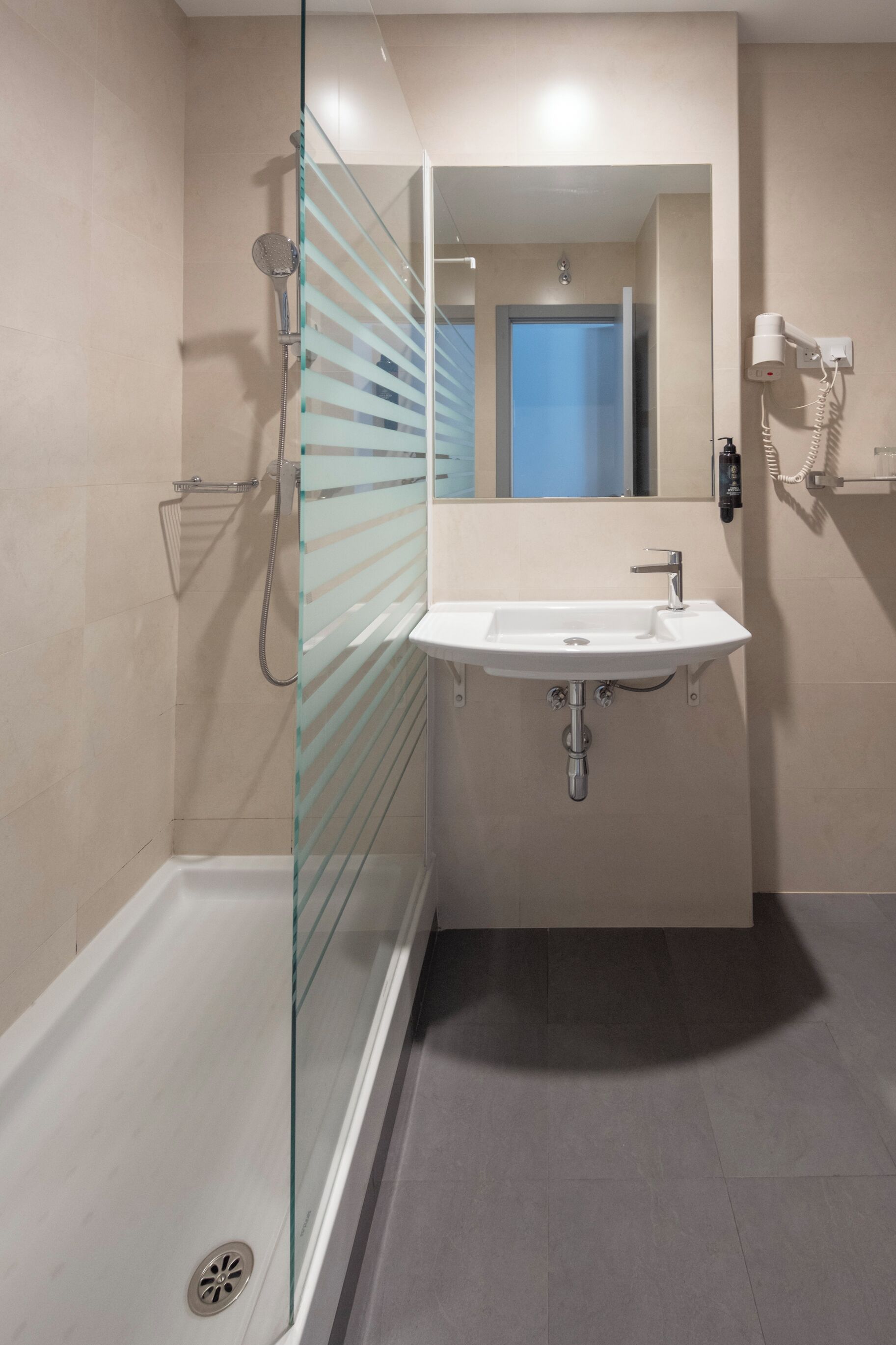 Een moderne badkamer met een douchecabine van glas, een wit wastafelmeubel en een spiegel.