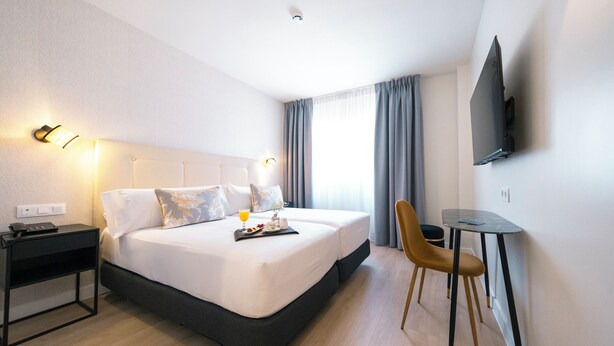 Una habitación de hotel con una cama grande, una mesita de noche y un escritorio pequeño con una silla.
