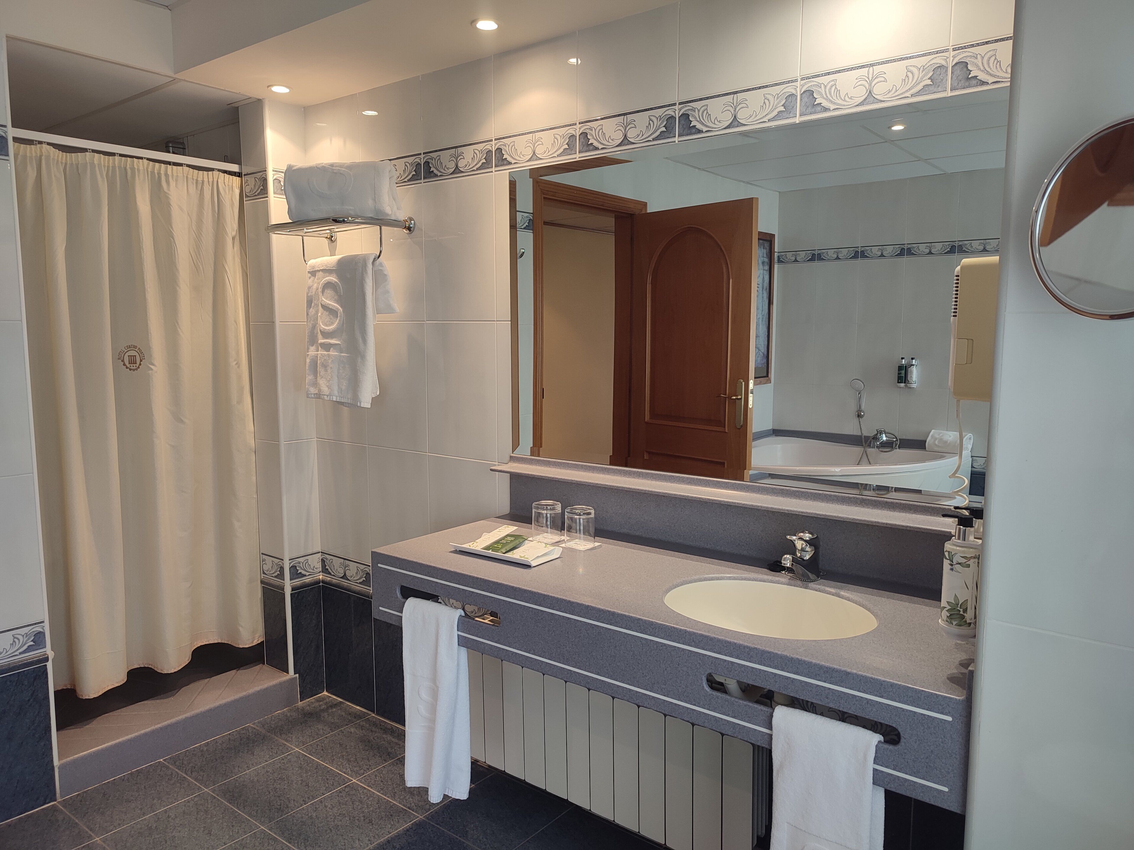 A modern bathroom with a large mirror, a bathtub, and a sink.