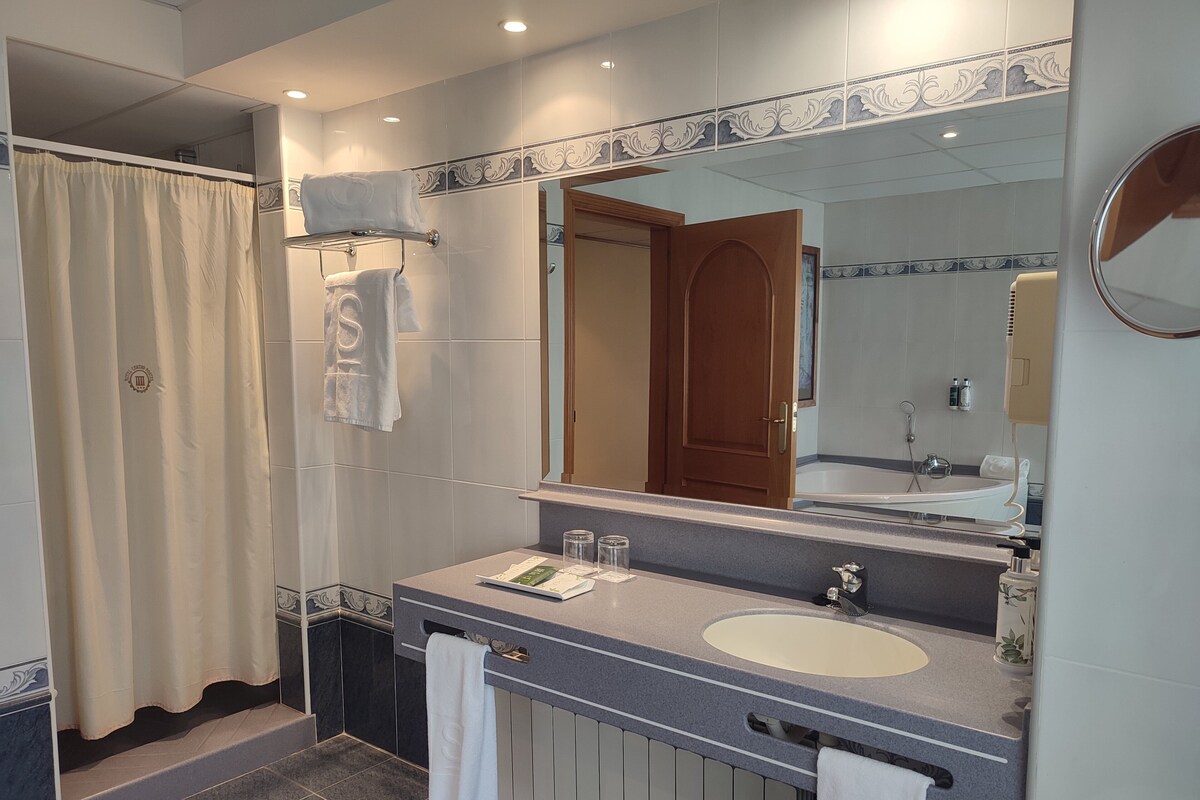 Un baño moderno con un espejo grande, una bañera y un lavabo.
