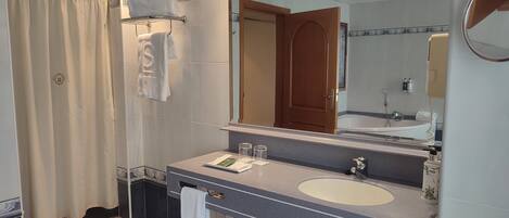 A modern bathroom with a large mirror, a bathtub, and a sink.