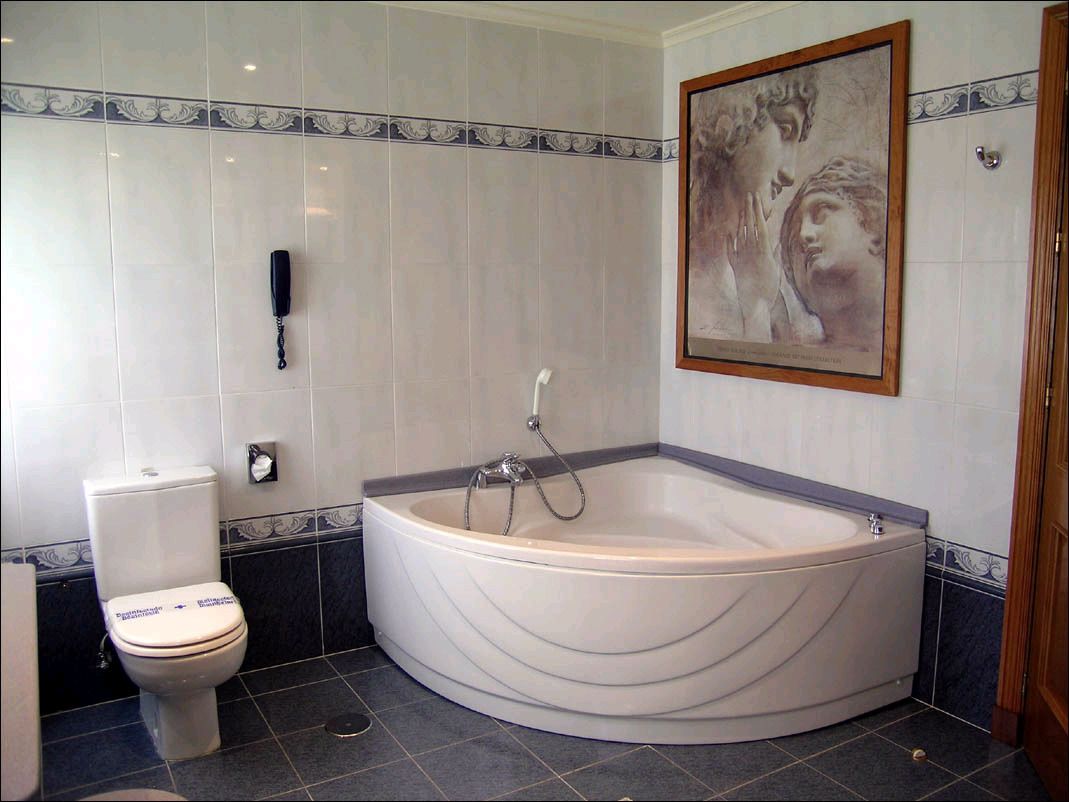 A bathroom with a toilet, bathtub, and a framed artwork on the wall.