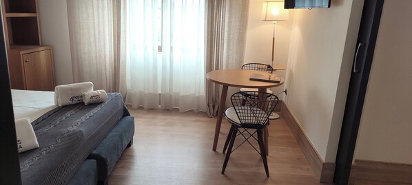 A hotel room with a bed, a small table with a chair, a lamp, and a window with curtains. - Hotel Sercotel Cuatro Postes (Ávila)