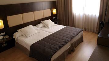 Ein Hotelzimmer mit einem großen Bett, einem Nachttisch mit Lampe und einem Schreibtisch.