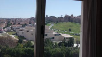 Vista a través de una ventana de un edificio de diseño arquitectónico moderno, con una combinación de techos planos y inclinados, y un amplio espacio abierto en primer plano.