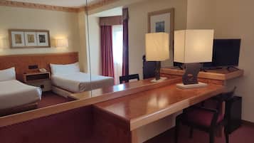 A hotel room with two beds, a desk with a chair, a television, and a mirror.