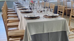 Uma sala de jantar com mesas preparadas para uma refeição, cadeiras e vista para a paisagem urbana.