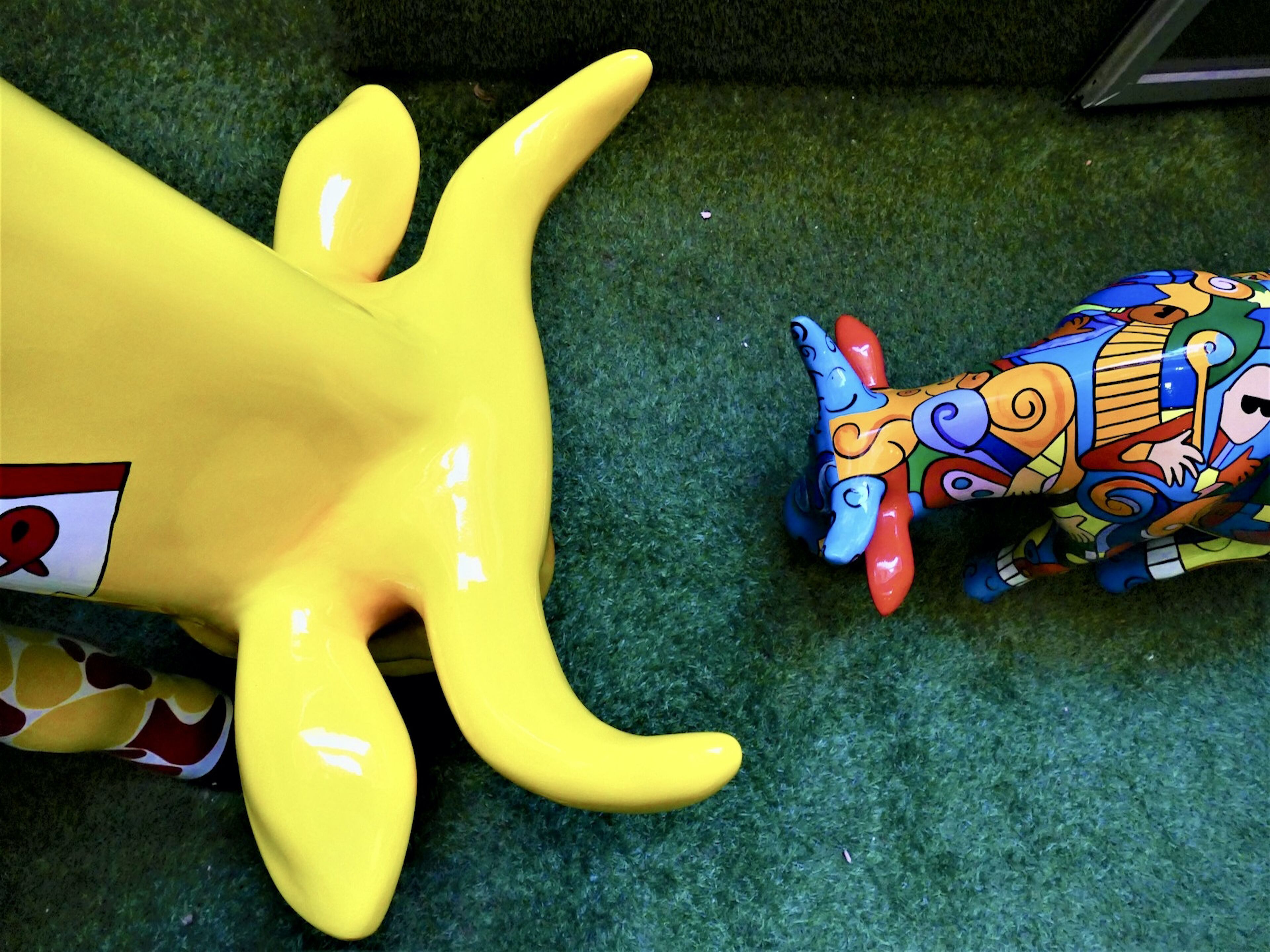 A yellow plush toy and a colorful, patterned toy on a green carpet.