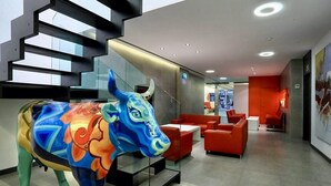 A modern lobby with a colorful bull sculpture, red seating, and a staircase. - Hotel Turin  Barcelona  (Barcelona)