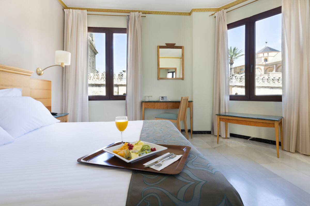 Une chambre d’hôtel avec un lit, un plateau de petit-déjeuner et un bureau avec une chaise.
