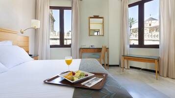 Une chambre d’hôtel avec un lit, un plateau de petit-déjeuner et un bureau avec une chaise.