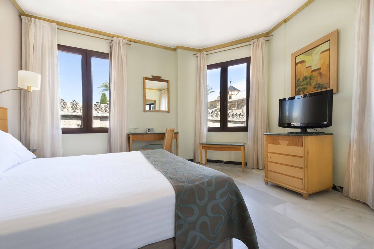 Une chambre d’hôtel comprenant un lit, un bureau, une chaise, une télévision et une commode.