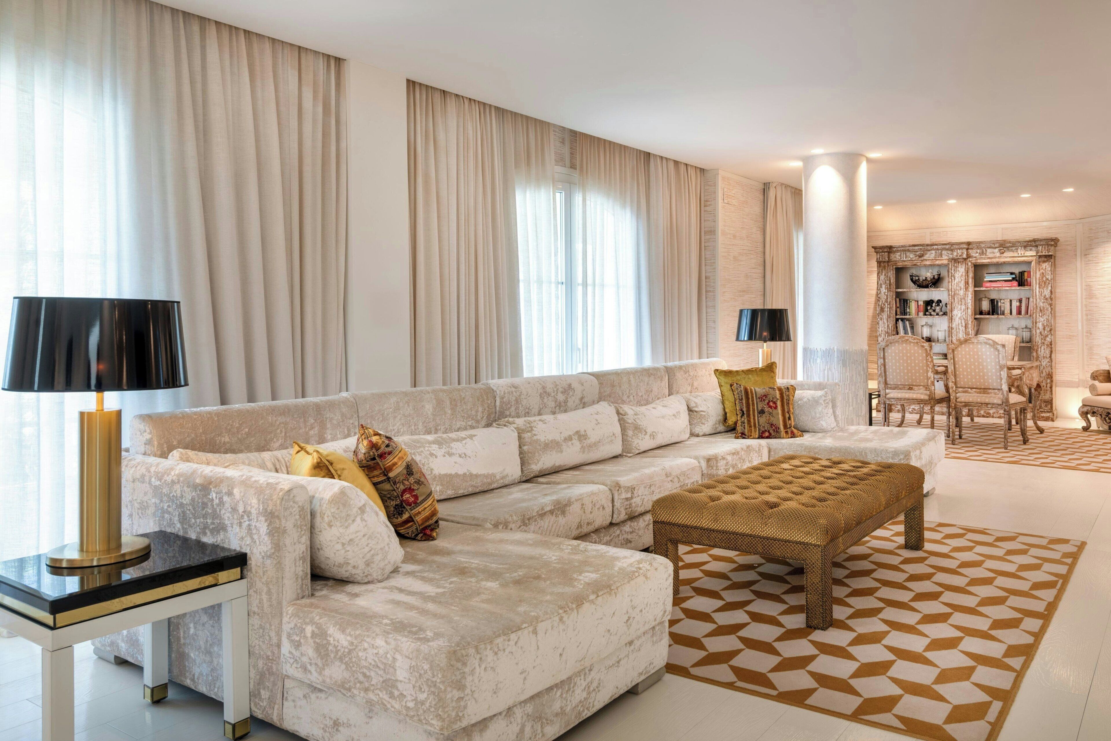 Una sala de estar con sofá, reposapiés y una alfombra estampada.