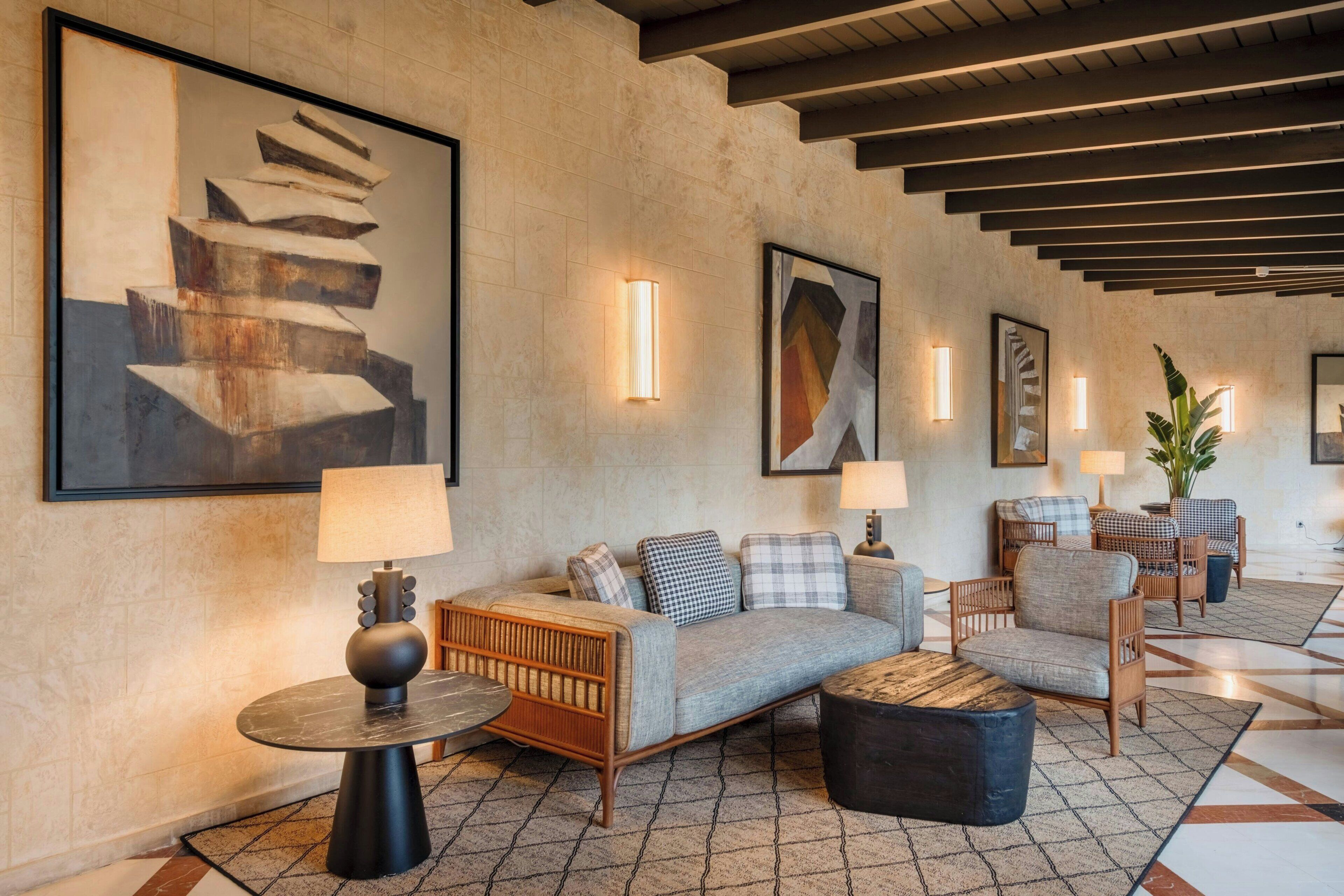 A lobby with a sofa, chairs, a round table, and artwork on the walls.