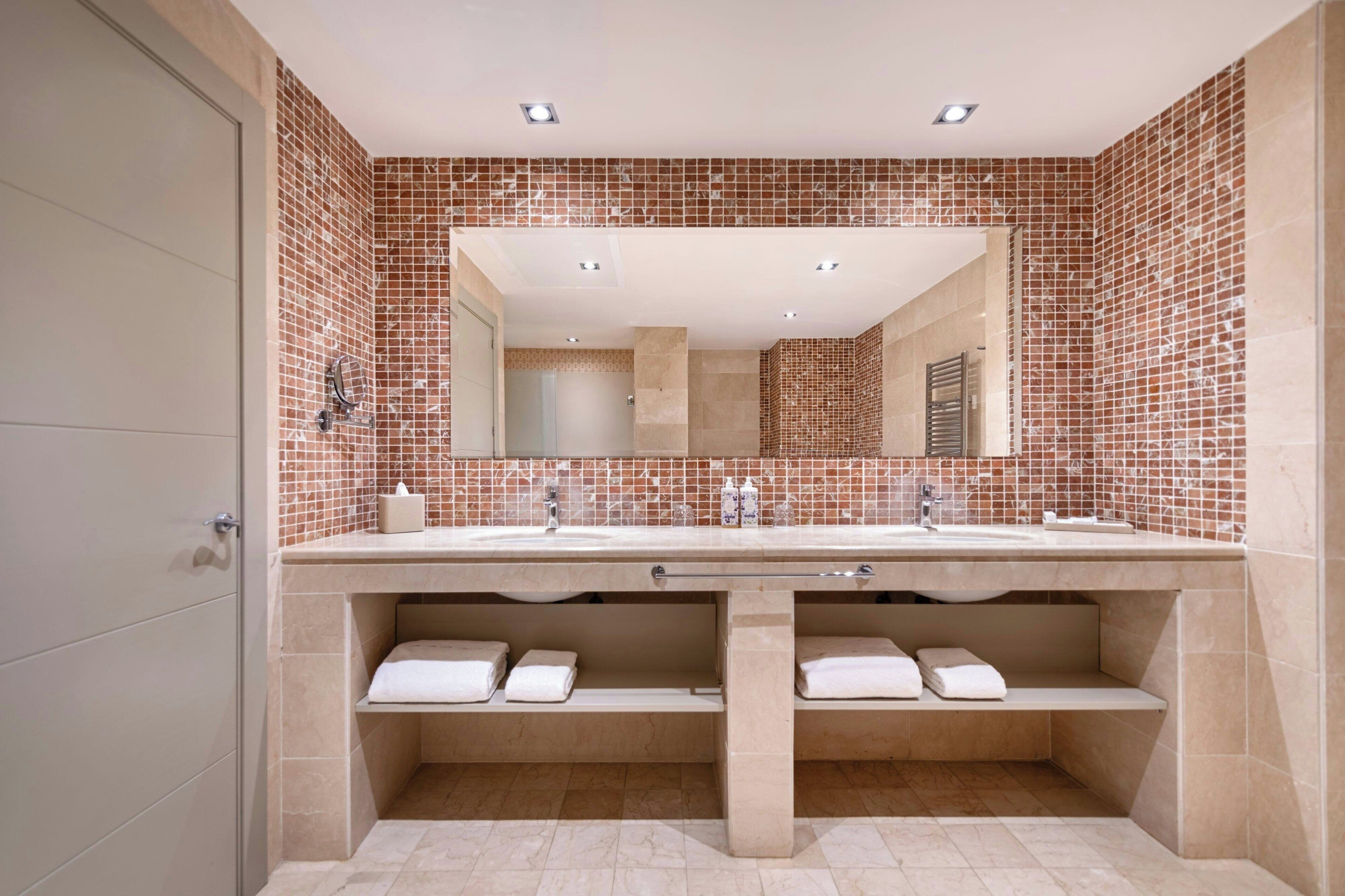 Un baño con un espejo grande, dos lavamanos y un salpicadero de azulejos.