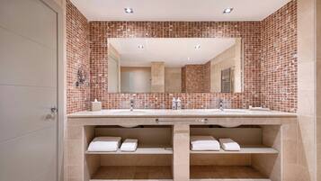 Un baño con un espejo grande, dos lavamanos y un salpicadero de azulejos.