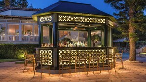 A gazebo-style bar with a glass enclosure, surrounded by outdoor seating. - Grand Hotel Las Dunas, Autograph Collection (Estepona)