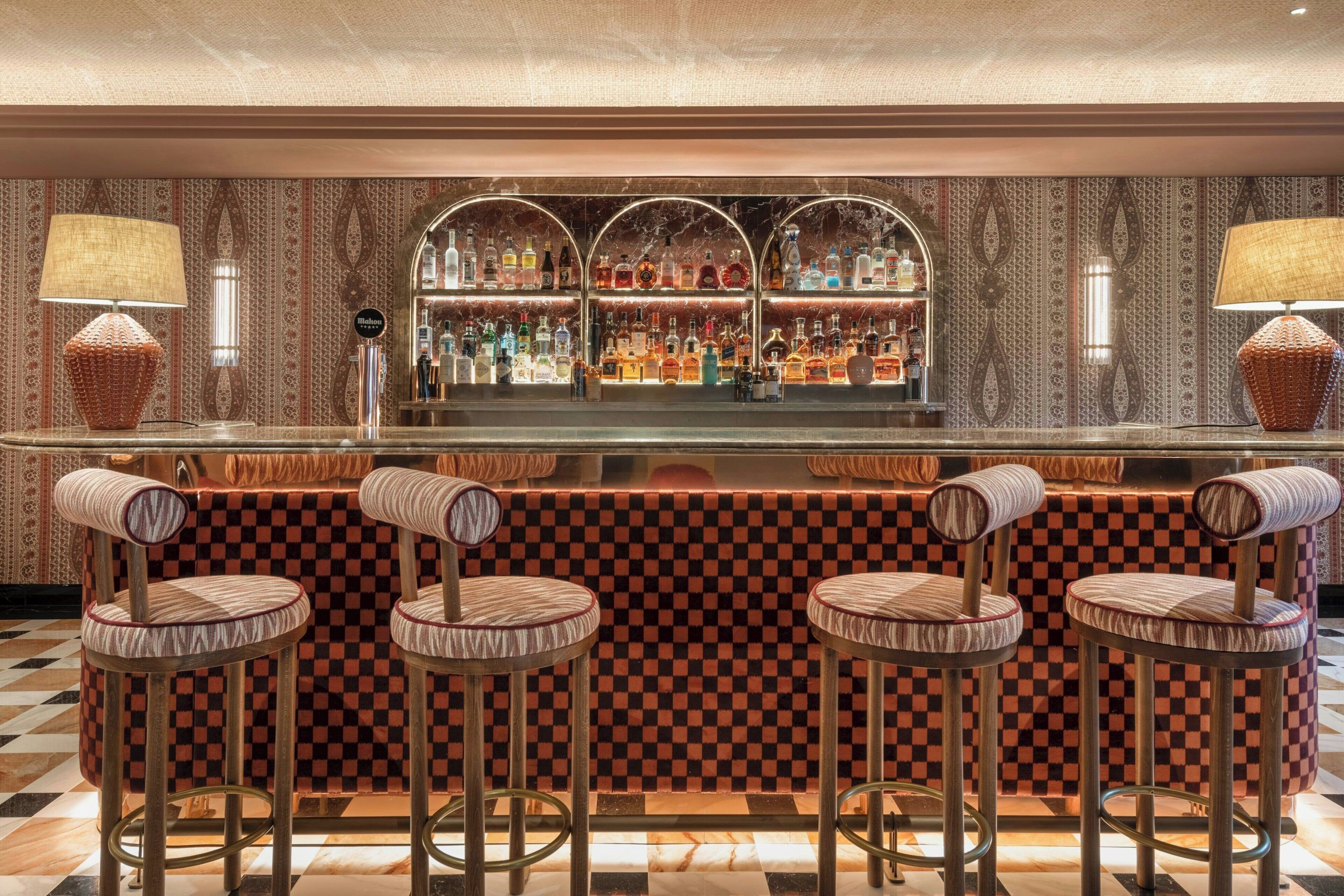 A bar area with checkered bar stools, a marble countertop, and a patterned wall.