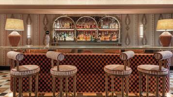 A bar area with checkered bar stools, a marble countertop, and a patterned wall.